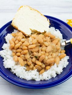 a blue plate topped with rice and beans next to a slice of bread on top of it