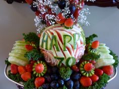 an arrangement of fruits and vegetables with the word arp carved into them on a platter