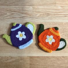 two crocheted pot holders sitting on top of a wooden floor next to each other