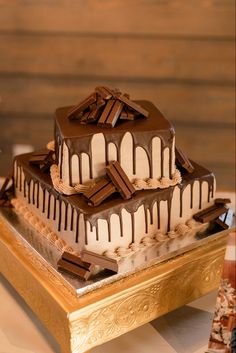 two tiered cake with chocolate and white frosting on a gold platter next to other desserts