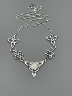 "I've fabricated a Celtic Irish inspired necklace with a center Celtic knot which features a center 8mm round cabochon, of your choosing in the drop down menu, with a total of three component pieces on either side. The sterling chain of 16 inches is soldered to each end making the approximate length of this piece just a bit over 18\" total. The chain will have a sturdy lobster claw. I've fabricated everything in sterling silver - it's a heirloom piece! This is a beautiful and feminine statement Adjustable Moonstone Birthstone Necklaces, Silver Teardrop Pendant Necklace With Cabochon, Silver Cabochon Necklace With Teardrop Pendant, Teardrop Cabochon Necklace For Anniversary, Anniversary Cabochon Teardrop Necklace, Anniversary Teardrop Cabochon Necklace, Adjustable Cabochon Necklace As Gift, Nickel-free Moonstone Necklace With Round Pendant, Moonstone Cabochon Round Pendant Necklace