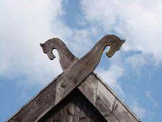 the roof of a building with a bird on it's side and clouds in the background