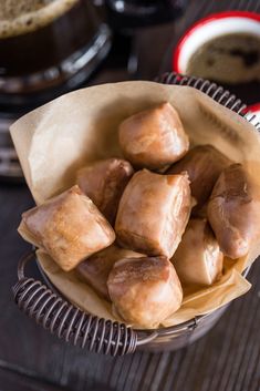 a bowl filled with donuts sitting on top of a table next to a cup of coffee