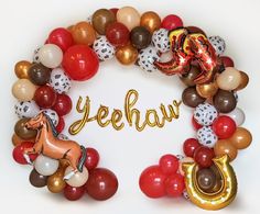 a wreath made out of balloons with the word yeehaw spelled in gold