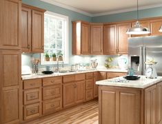 a large kitchen with wooden cabinets and white counter tops, along with hardwood flooring