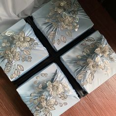 four blue boxes with flowers on them sitting on a wooden floor next to a bed