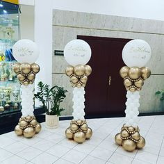 two tall gold and white balloons are on display in front of a storefront door