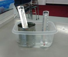 two measuring cups sitting on top of a table next to some books and pencils