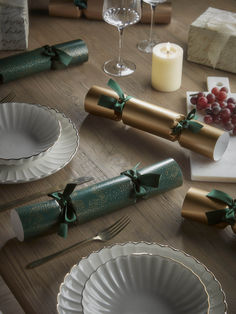 the table is set with wine glasses, silverware and wrapped gift wrappers on it