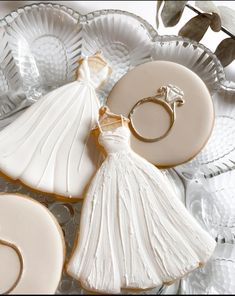 a bride's dress, ring and cookies are arranged on a platter for display