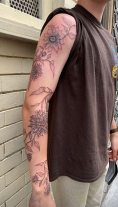 a man with a sunflower tattoo on his arm is standing next to a building