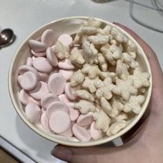 a hand holding a bowl filled with marshmallows