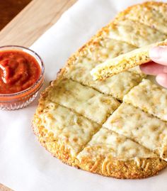 a person dipping some crackers into a pizza crust with ketchup on the side