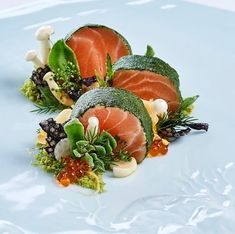 three pieces of salmon on a plate with mushrooms and broccoli in the center