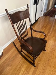 a wooden rocking chair sitting on top of a hard wood floor next to a door