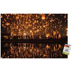 many lanterns are floating in the air over water at night, with people standing around