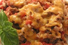 a close up of a plate of food with meat and cheese on top, garnished with green leaves