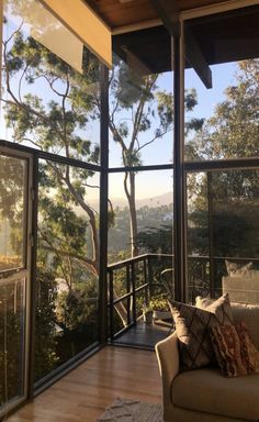 a living room filled with furniture and lots of glass doors that look out onto the trees