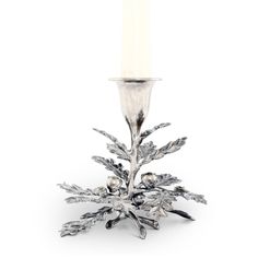 a silver candle holder with a white candle on it's side and snowflakes around the base