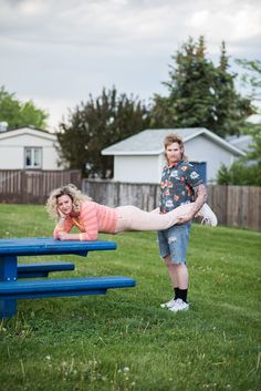 a woman and her daughter are playing in the grass with a blue picnic table outside