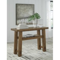 a wooden table sitting in front of a painting on the wall next to a potted plant