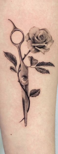 a rose and scissors tattoo on the thigh