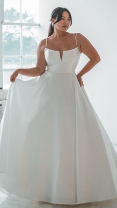 a woman in a white dress is posing for the camera with her hands on her hips