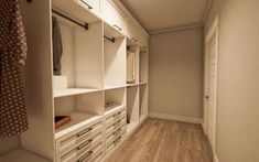 an empty walk in closet with white cabinets and drawers on the wall, next to a wooden floor