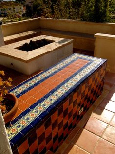 a tiled bench sitting on top of a patio next to a potted planter