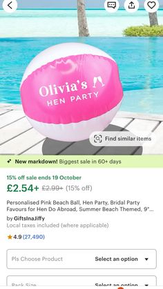 an inflatable pink beach ball sitting on top of a wooden deck next to the ocean