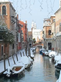 a canal with boats covered in snow next to buildings