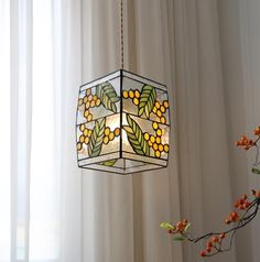 a stained glass lantern hanging from a ceiling in front of a window with white drapes