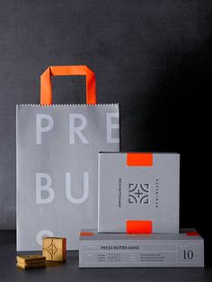 two paper bags, one with an orange ribbon and the other with a white bag