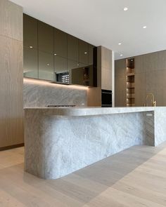 an empty kitchen with marble counter tops and cabinets in the back ground, along with wooden flooring