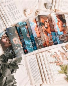 a bunch of books sitting on top of a bed next to flowers and an open book