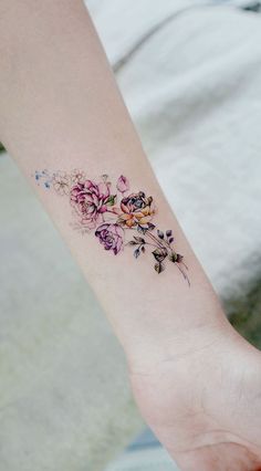 a small flower tattoo on the left inner forearm and foot, with pink flowers all over it