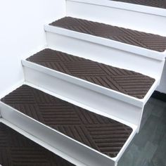 the stairs are covered in brown carpet and white trims, with black treading on each step