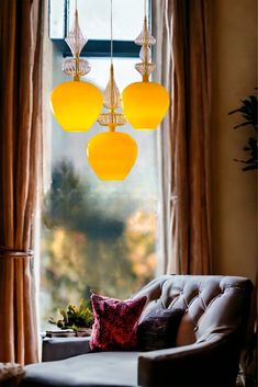 a living room filled with furniture next to a window covered in yellow curtains and hanging lights