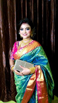 a woman in a colorful sari holding a clutch and posing for the camera with her hands on her hips