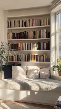 a white couch sitting in front of a window filled with lots of bookcases