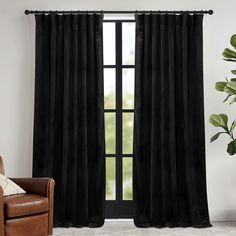 the black velvet curtains are hanging in front of a window with a brown chair and potted plant