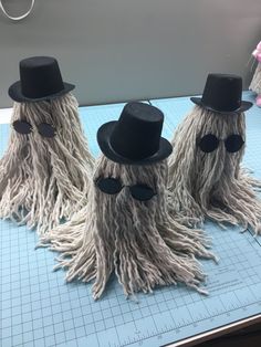 three fake mop legs with hats and glasses on top of a cutting paper board