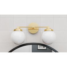 two white balls are hanging on the wall next to a mirror with a gold trim