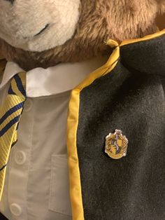 a teddy bear wearing a suit and tie with a pin on it's lapel