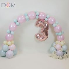 the balloon arch is decorated with pastel balloons and a large number 3 balloon in the shape of a letter