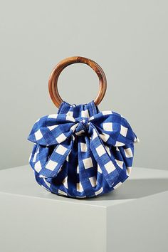 a blue and white checkered purse with a wooden handle sitting on top of a block