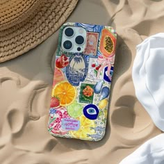 an iphone case is laying on the sand next to a straw hat and sunhat