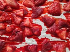 sliced strawberries on top of white paper with red liquid flowing down the side and over them