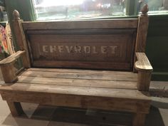 a wooden bench sitting in front of a window with the word chevy written on it