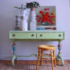 a green table with two vases on it and a stool in front of it